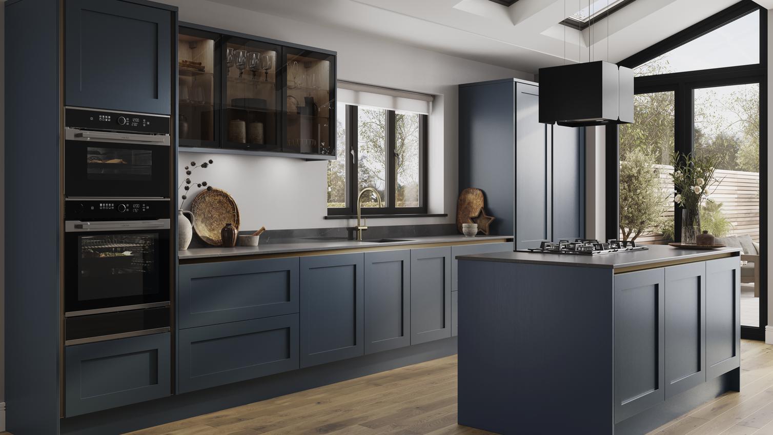 An island kitchen layout with blue shaker doors, black worktops, wood floors, and bronze profiles for a handleless look. 